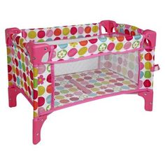 a pink baby crib with colorful polka dots on the top and bottom, in front of a white background