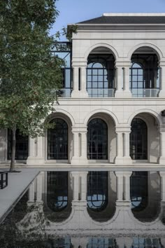 a large white building with many windows reflecting in the water