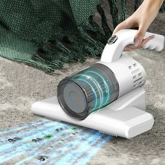 a person using a handheld vacuum to clean carpet with blue and green light coming from it