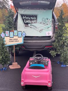 a pink toy car parked in front of a van with its trunk open and the back door open