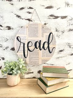 a wooden sign that says read next to some books and a potted plant on a table