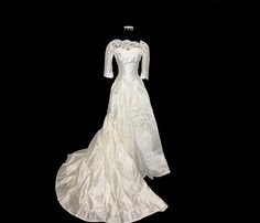 a white wedding dress on display against a black background