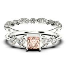 an engagement ring set with a pink diamond in the center and two white diamonds on each band