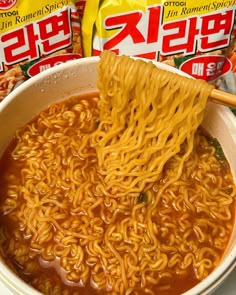 a bowl of ramen with chopsticks in it and two packets of noodles on the side