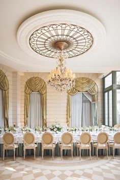 an elegant dining room with chandelier and white tablecloths, gold chairs