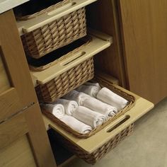 two wicker baskets with towels in them are sitting on the floor under a cabinet