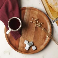 a wooden plate topped with marshmallows next to a cup of coffee