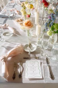 the table is set with silverware and flowers