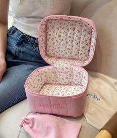 an open pink suitcase sitting on top of a white couch next to a woman's leg