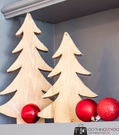 a wooden christmas tree sitting on top of a shelf next to ornaments and a red ornament