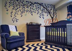 a baby's room decorated in blue and yellow with a tree decal on the wall