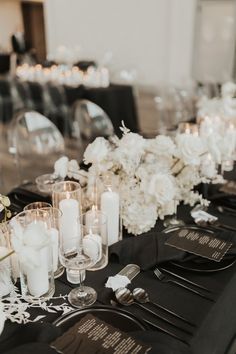 a long table is set with white flowers and black linens for an elegant wedding reception