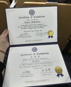 two diplomas are being held up in front of each other with writing on them