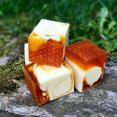 three pieces of soap sitting on top of a rock covered in brown and white liquid