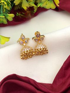 These American Diamond Small Gold Jhumka Earrings with Ruby Emerald CZ color stones are perfect for daily wear. Crafted with 22k gold tone, these earrings feature ruby and emerald stones fashioned in a classic small jhumka design. Ideal for an elegant look, these Indian earrings are sure to become an instant favorite. Small Gold Jhumka, Gold Buttalu, Small Jhumka, Jhumka Design, Gold Jhumka, Jhumka Designs, Gold Jhumka Earrings, Color Stones, Ruby Emerald