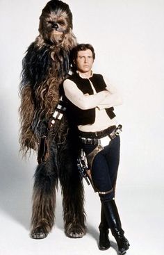 a woman standing next to a man dressed as chew - oo and star wars character