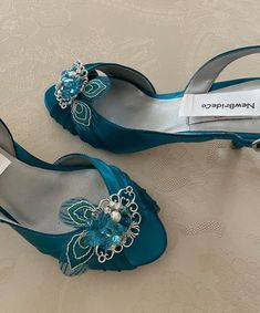 a pair of blue shoes with flowers and pearls on the toes are sitting on a bed