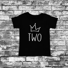 a black t - shirt with the word two on it hanging from a brick wall