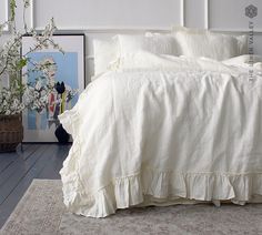 a bed with white linens and ruffled bedspread in a bedroom setting