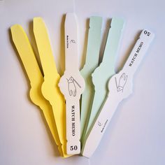 five different colored paper knives on a white surface