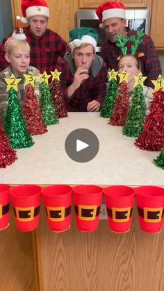 a group of people sitting around a table with christmas decorations on it and cups in front of them