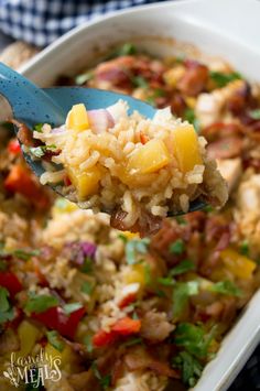 a spoon full of food with rice and vegetables on it is being lifted from a casserole dish