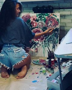 a woman is sitting on the floor painting