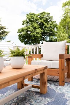 a wooden table sitting on top of a blue rug next to a chair and coffee table