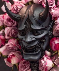 a black mask surrounded by pink roses