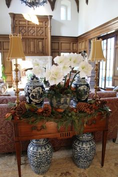 two blue and white vases sitting on top of a table with flowers in them