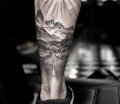 a man's foot with a mountain scene on it and a cross in the middle