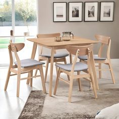 a dining room table with chairs and pictures on the wall behind it in front of a window