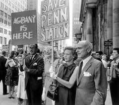 black and white photograph of people holding signs on the street with buildings in the background