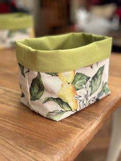 a bag sitting on top of a wooden table next to a green cloth covered container