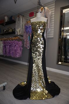 Get your shine on in this BEAUTIFUL gown! Covered in gold mirrored plates down the center of the front and back, top to bottom. Features a strapless silhouette and has good stretch. Has a train that will follow you while you walk through the room. ;) A gala, your birthday party, any occasion that you want to make a statement, this is the piece you need. Item has some stretch, but be sure to stay within your size range for the best fit. Top of dress is not a structured bustier. Embellishments are Gold Strapless Gown For Prom Season, Gold Strapless Gown For Gala, Glamorous Gold Strapless Gown, Strapless Gold Evening Gown, Gold Strapless Evening Gown, Fitted Sequin Gown For Glamorous Events, Jumpsuit Jacket, Leggings Sale, Maxi Gowns