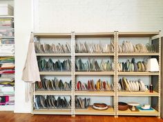 a book shelf filled with lots of books on top of wooden floor next to a white brick wall