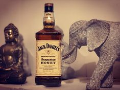 an elephant figurine next to a bottle of jack daniels honey on a shelf