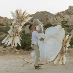 a man and woman are kissing in front of a circular frame with feathers on it