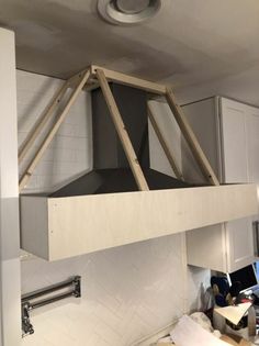 a stove top oven sitting inside of a kitchen next to a wall mounted exhaust fan