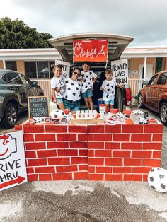 some kids are standing in front of a red brick wall with white and black decorations