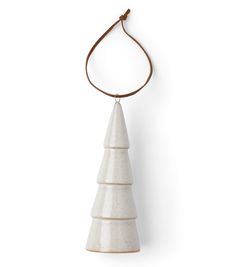 a white ceramic ornament hanging from a cord on a white wall with a brown string