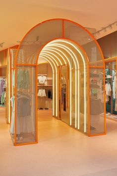 the inside of a clothing store with an archway and neon lights on the wall above it