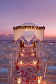 the aisle is decorated with candles and flowers for an outdoor wedding ceremony on the beach