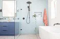 a bathroom with blue and white walls, a bathtub, shower head, and mirror