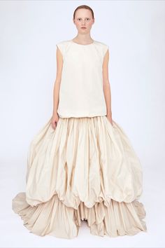 The Mayla dress is the second bridal look of the Molly Goddard Spring Summer 2023 runway collection. This sleeveless dress is crafted from Spanish cream taffeta and features a relaxed bodice with a voluminous skirt that's carefully hand-gathered into bubble tiers. To create the dramatic silhouette, the bubble skirt is draped over an asymmetric train of taffeta. This full length bridal dress has a midweight, non-stretch fabric. #MGBridal How To Create A Fashion Collection, Luxury Cream Dress With Voluminous Skirt, Chic Tiered Voluminous Skirt, Chic Voluminous Tiered Skirt, Taffeta Gathered Skirt, Silk Dress With Voluminous Gathered Skirt, Spring Bubble Dress With Voluminous Skirt, Runway Skirts, Painted Ballerina