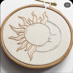 a sun and moon embroidered on a wooden hoop with stitching in the hoop around it