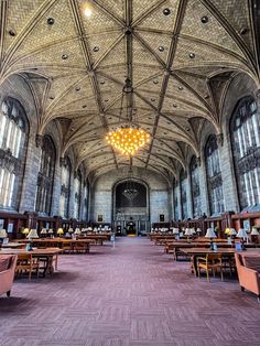 the inside of a large building with tables and chairs in front of it, along with chandeliers hanging from the ceiling