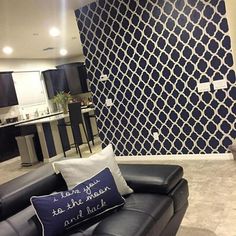 a living room filled with furniture and a large wall papered in pattern behind the couch