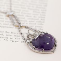 This antique amethyst and diamond drop necklace is truly something special - on the neck, it almost feels like an amulet that holds so much magic and life! Amethysts hold so much meaning, and are thought to bring cleansing, peaceful, and calming energy to the one wearing them. This heart-shaped cabochon has the dreamiest, deeply purple color to it, surrounded by a bow motif studded in rose cuts. Not to mention, the old mine cut and elongated oval diamond component that it hangs off of! This neck Luxury Purple Diamond Necklace, Fine Jewelry Heart-shaped Amethyst, Amethyst Heart Cut Necklace For Anniversary, Heart Cut Amethyst Necklaces For Anniversary, Elegant Heart-shaped Amethyst Necklace, Heart Cut Amethyst Necklace For Anniversary, Purple Heart Pendant Necklace For Formal Occasions, Formal Purple Heart Pendant Necklace, Purple Diamond Necklace Fine Jewelry