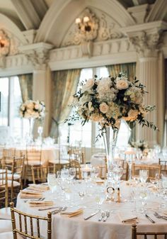 the tables are set up with white linens and gold chairs for an elegant wedding reception